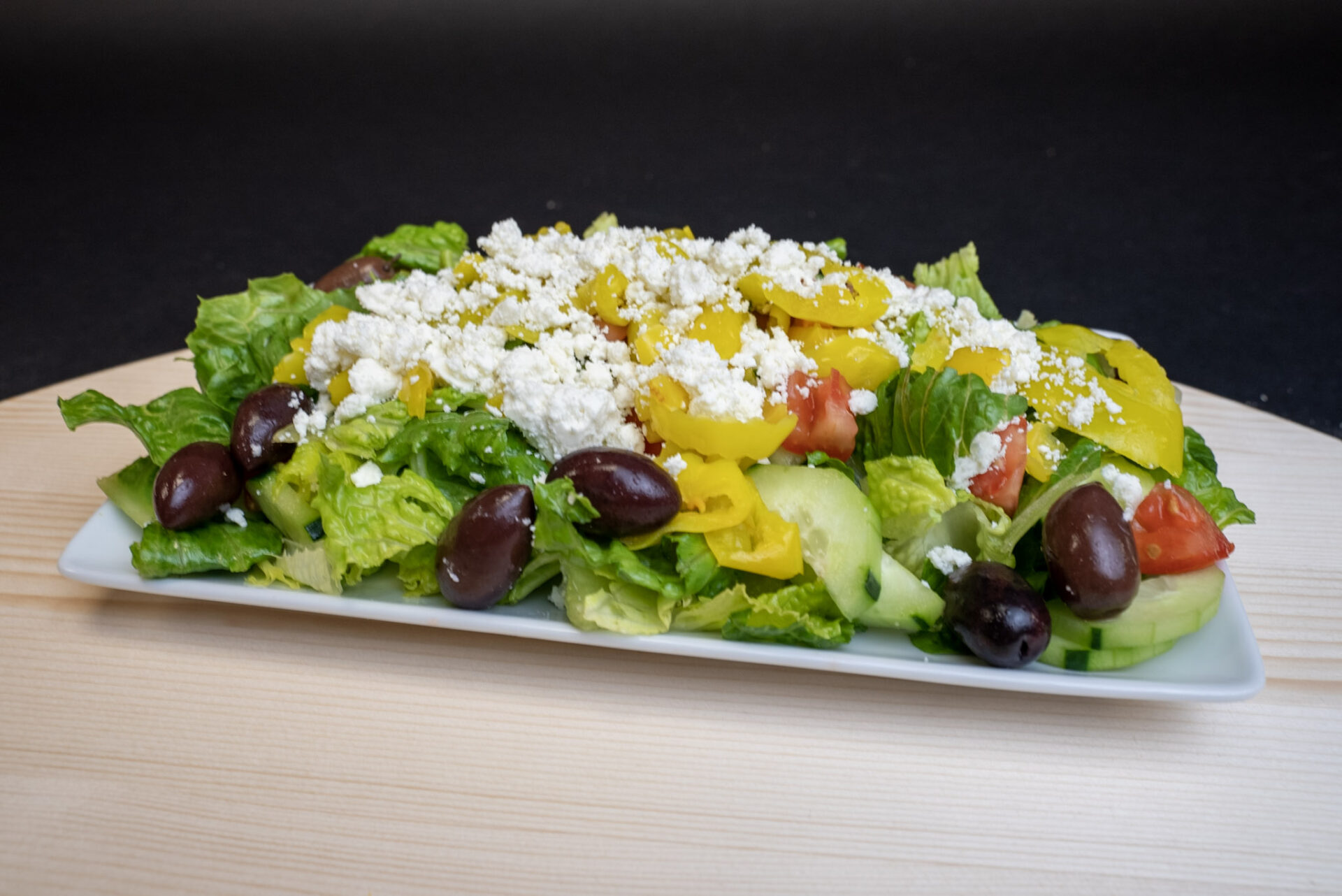 A plate of salad with feta cheese and olives.